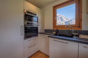 A kitchen with a built-in oven, a sink, and a window with a mountain view. - Chalet Skyline Mont Blanc, Servoz (Chamonix), France (Servoz (Chamonix))