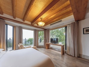 Une chambre d’hôtel avec un grand lit, une télévision et un balcon avec des rideaux.