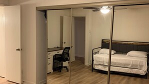 Ein Schlafzimmer mit einem Bett, einem Schreibtisch, einem Stuhl und einem Deckenventilator.