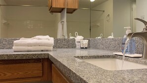 Ein Badezimmer mit Granitablage, Waschbecken, Spiegel und Holzschränken.