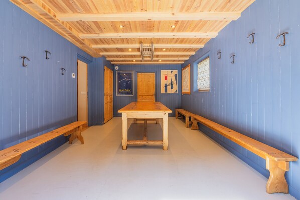 Um quarto com mesa e bancos de madeira, paredes azuis e vigas de madeira no teto.