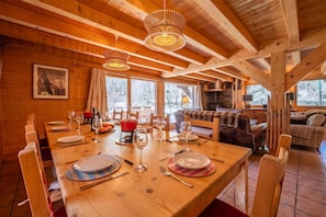 A wooden interior with a dining table set for a meal, a fireplace, and a cozy seating area. - Chalet Montet Forest River Garden Lodge, Vallorcine (Argentiere), France (Vallorcine (Argentiere))