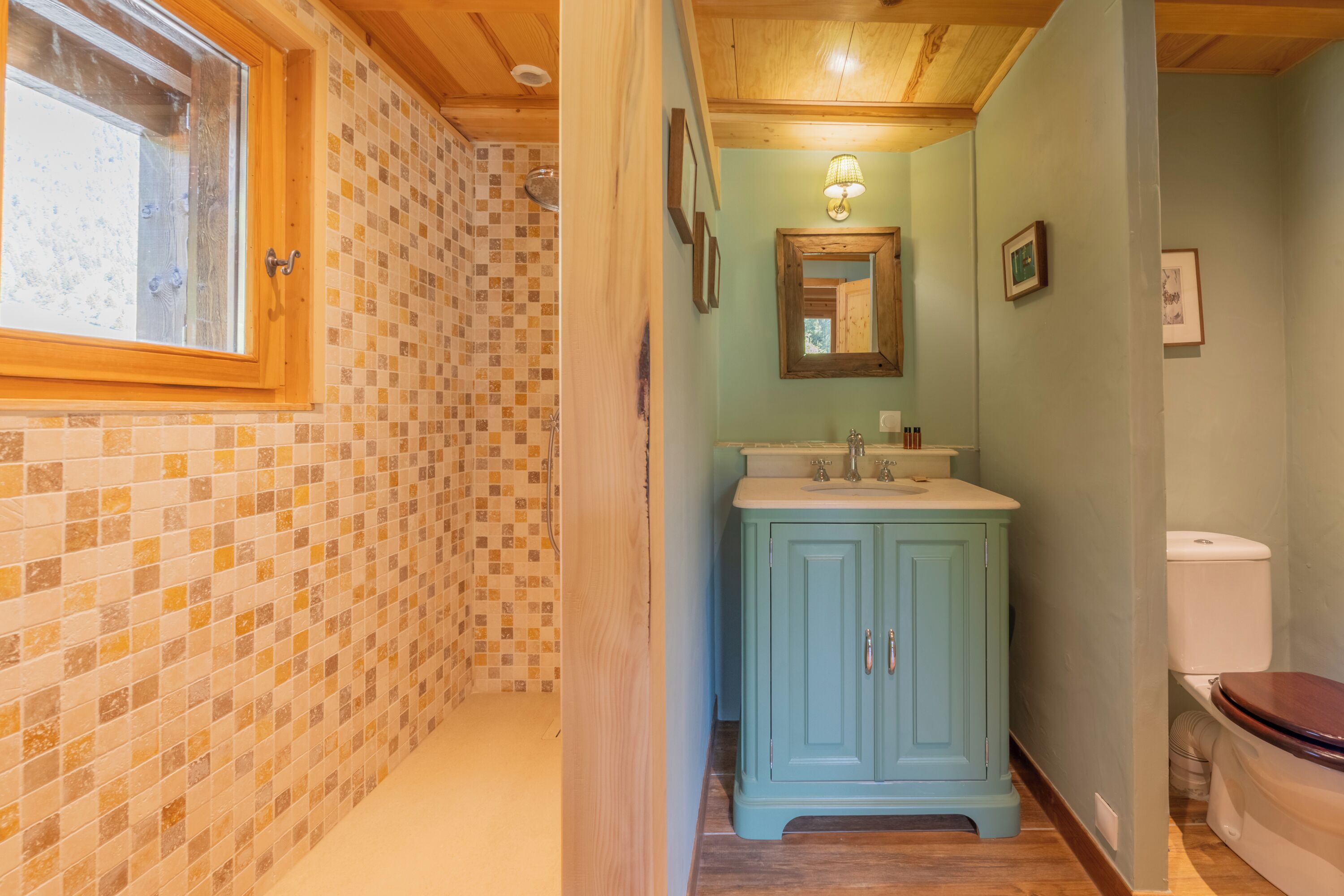 A bathroom with a tiled shower, a sink with a cabinet, and a toilet.
