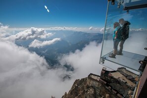 Plataforma de observação de vidro com vista desobstruída para nuvens e montanhas.