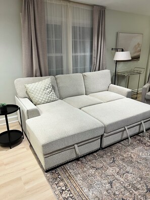 Una sala de estar moderna con un sofá modular, un tapete estampado, una mesita auxiliar y una lámpara de pie.