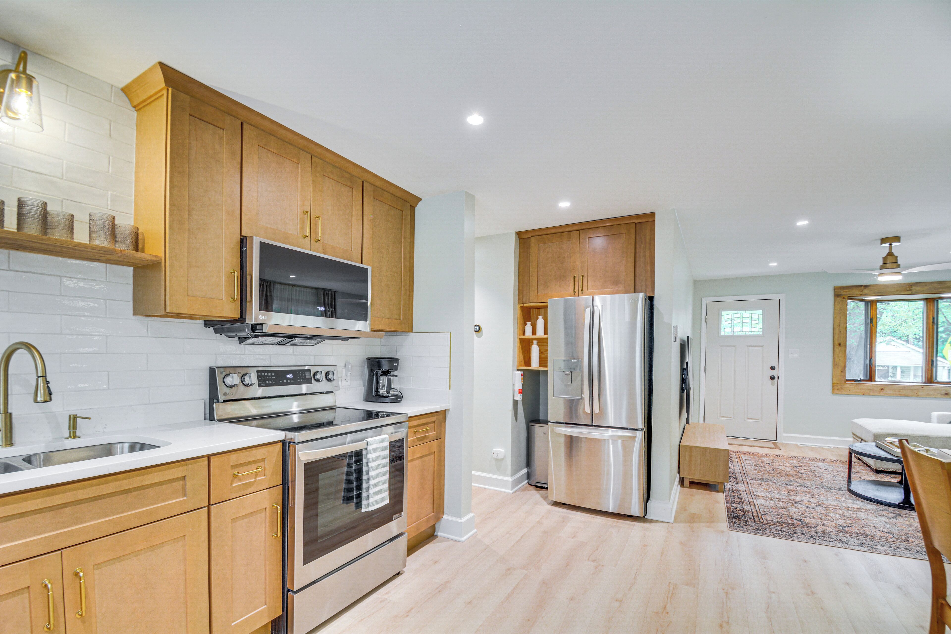 A modern kitchen with wooden cabinets, stainless steel appliances, and a built-in microwave.