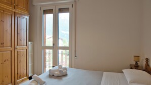 Une chambre d’hôtel avec un grand lit, une armoire en bois et une vue sur l’extérieur, visible à travers une porte vitrée.