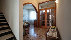 Una scala conduce a una stanza con una porta in legno, un piccolo tavolo con un vaso di fiori e un pavimento decorato.