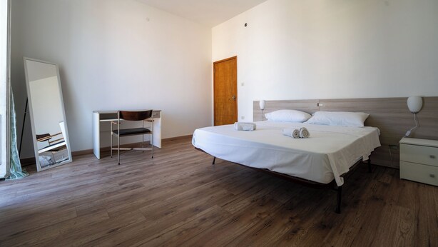 Una camera da letto con un letto, un comodino, una sedia e uno specchio.