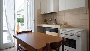 Una cocina con una mesa de madera, lavavajillas, estufa y armarios.