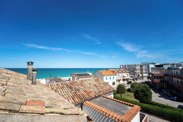 A hotel with a view of the sea, terracotta roof tiles, and a clear blue sky.