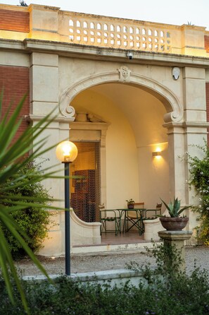 An arched entrance with a seating area, a lamp post, and potted plants. - Dimora Lustrelle con parco privato (Cutrofiano)
