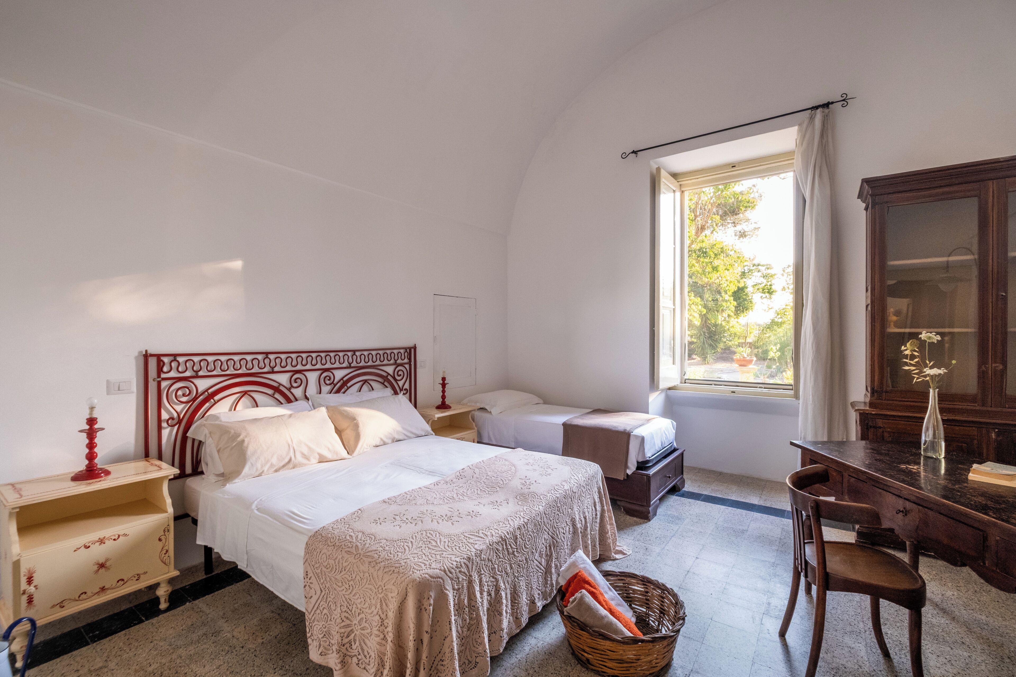 Ein Schlafzimmer mit einem Bett, Nachttischen, einem Schreibtisch und einem Fenster.