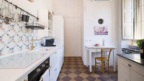 A compact kitchen with a sink, stove, and a dining area with a chair and table. - Dimora Lustrelle con parco privato (Cutrofiano)