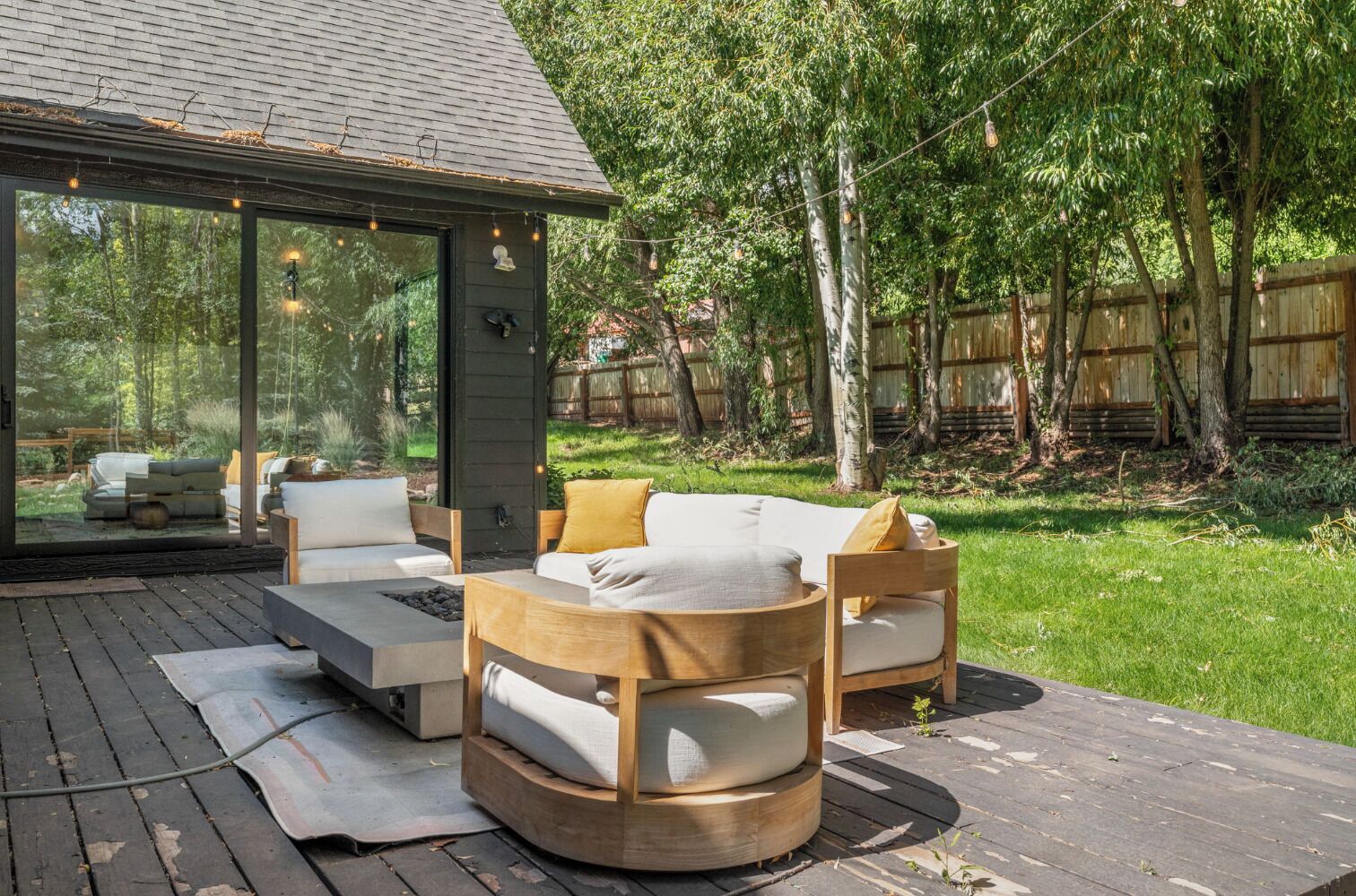 An outdoor deck with a sofa, chairs, and a fire pit.