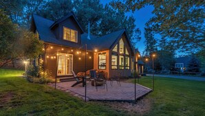 Ein Haus mit Terrasse, Sitzgelegenheiten im Freien und Lichterketten.
