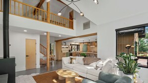 Ein geräumiger Wohnbereich mit hoher Decke, einer Treppe, einer Küche und einem Essbereich.