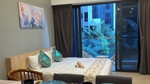 A hotel room with a bed, a dining table set with plates and cups, a chair, and a view of palm trees through a large window. - Cozy studio apartment with balcony near KLCC, TRX, Gleneagles, Ampg Puteri Hosp (Kuala Lumpur)