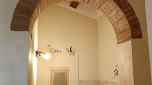 A bathroom with a tiled floor, a mirror, a towel rack, and a sign that says 'The Kitchen'.