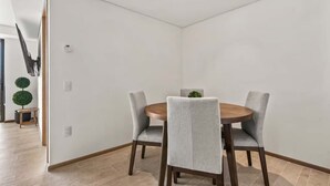 Un comedor con una mesa redonda, cuatro sillas tapizadas grises y una pequeña planta en maceta.