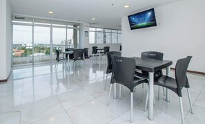 Un salón de conferencias moderno con una gran mesa, sillas, un televisor de pantalla plana y ventanas amplias que ofrecen vista a la ciudad.