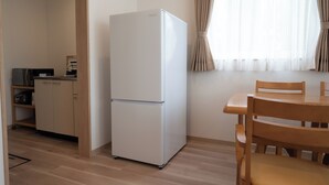 A compact kitchen with a white refrigerator, wooden cabinets, and a dining table with chairs. - Fuyu no Sonata 2 (Nakafurano)
