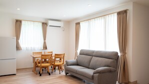 A living room with a sofa, wooden chairs, a dining table, and a kitchen area. - Fuyu no Sonata 2 (Nakafurano)