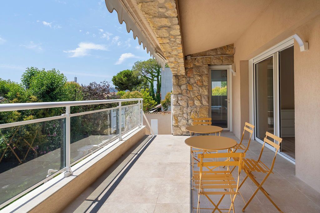 Un balcon doté d’une rambarde en verre, d’un mur en pierre et d’une porte donnant sur l’intérieur.