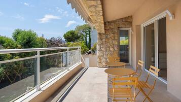Un balcon doté d’une rambarde en verre, d’un mur en pierre et d’une porte donnant sur l’intérieur.