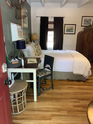 A bedroom with a bed, a desk, a chair, a lamp, a wardrobe, and a window with curtains.