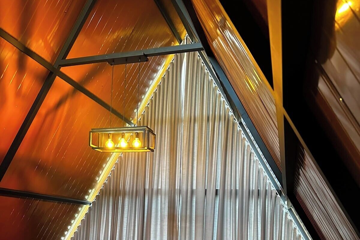 Un cuarto acogedor y triangular con una cama, una mesa con pétalos de rosa y una pequeña mesa redonda.