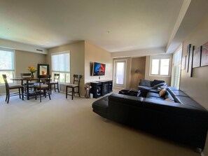 Sala de estar con sofá, televisor y comedor con sillas y una mesa.