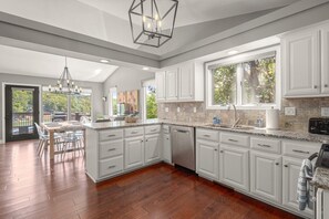 A spacious kitchen with white cabinetry, a large island, and a view of the outdoors.