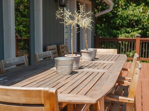 An outdoor wooden table with metal buckets and a potted plant.