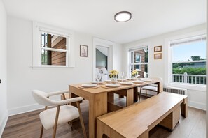 Ein Essbereich mit einem Holztisch, gedeckt für sechs Personen, weißen Stühlen und einer Bank.
