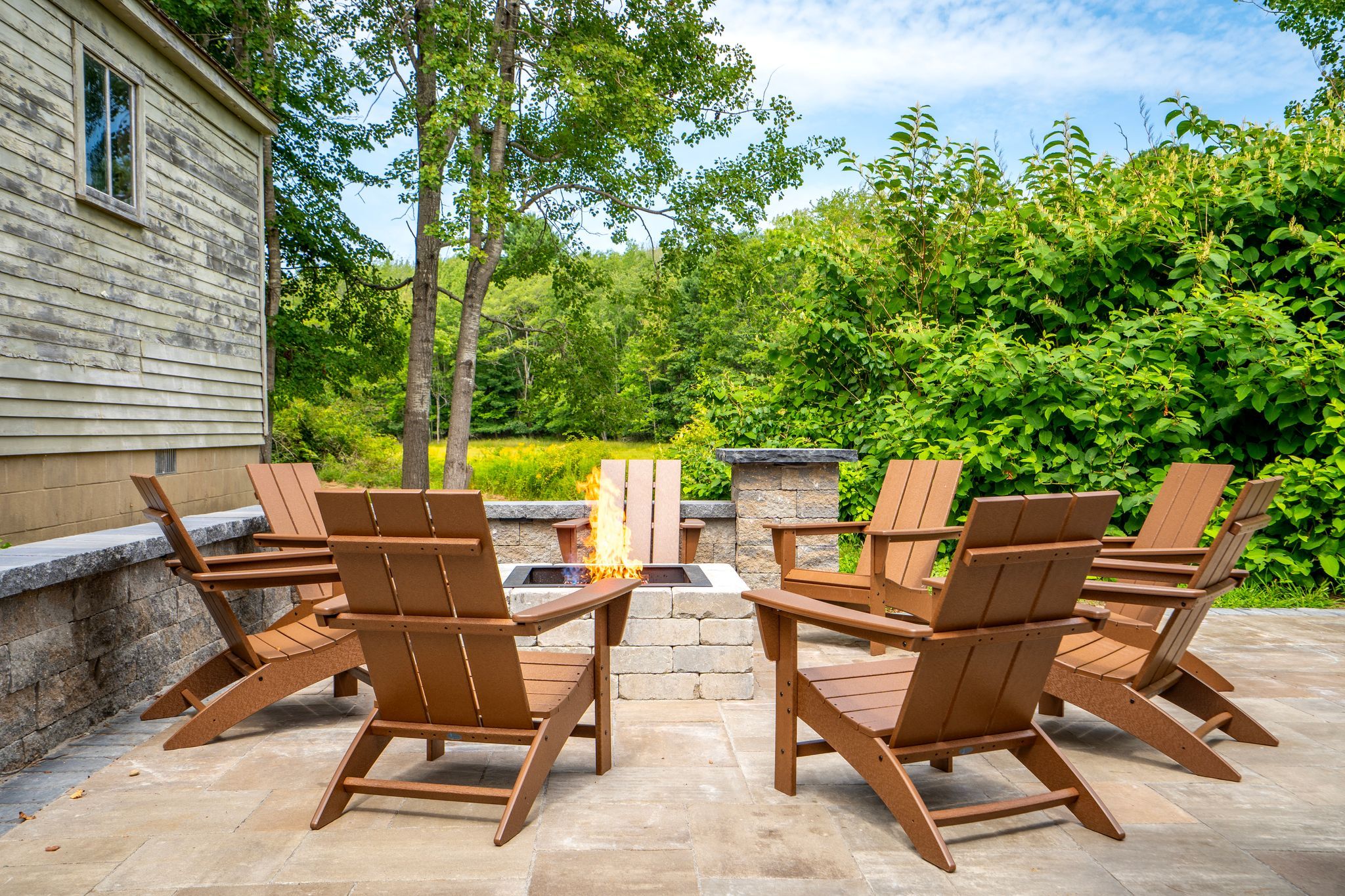 A patio with Adirondack chairs and a stone fire pit.