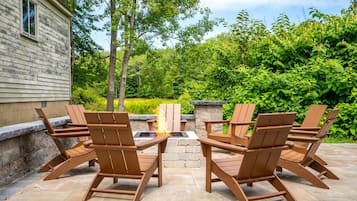 A patio with Adirondack chairs and a stone fire pit.
