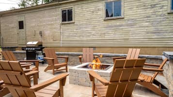 An outdoor seating area with Adirondack chairs and a fire pit.