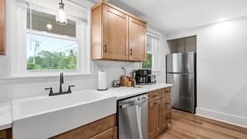 A modern kitchen with wooden cabinets, stainless steel appliances, and a white countertop.