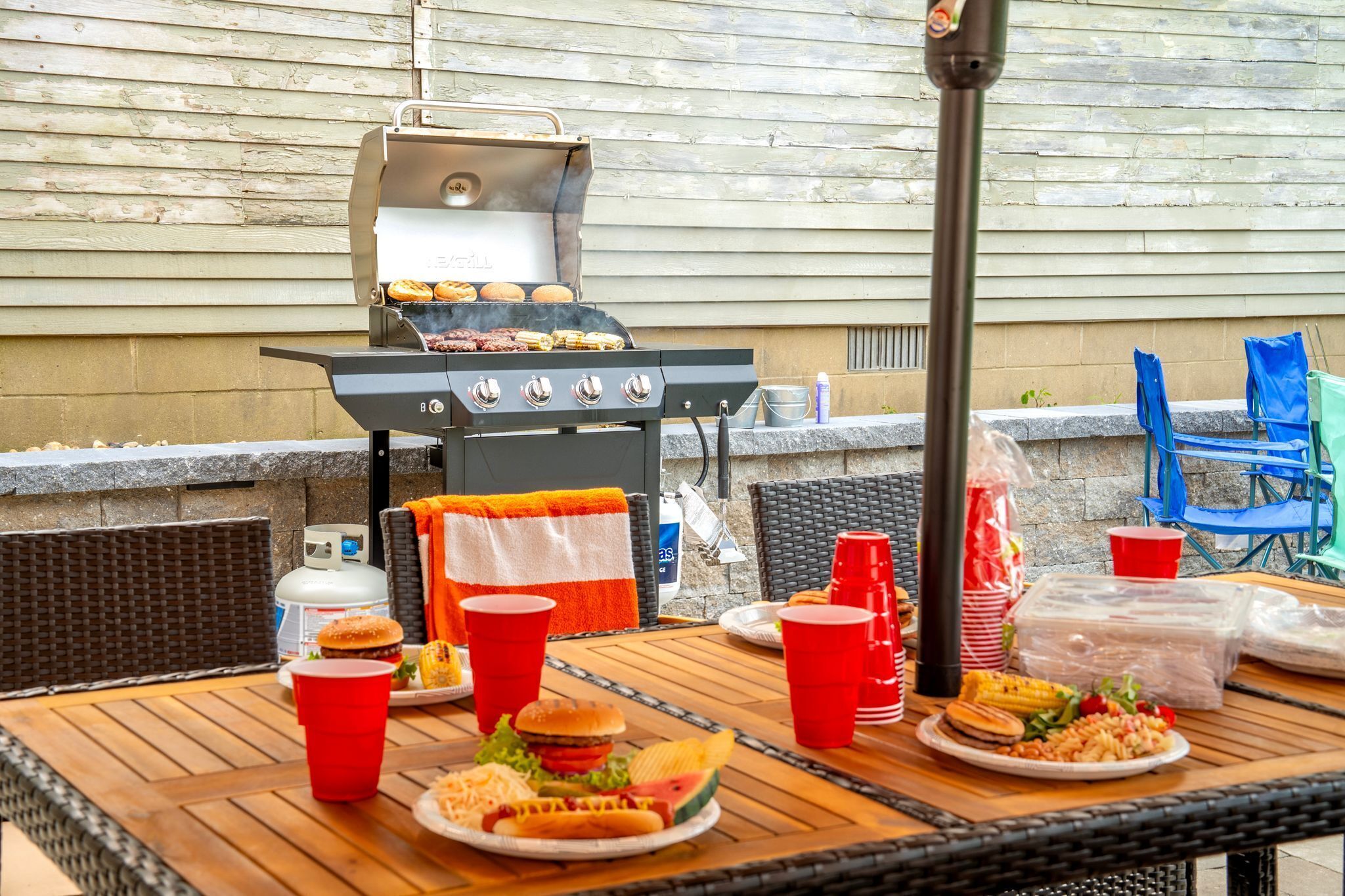 Een terras met eethoek, een barbecue, rieten stoelen en etenswaren.