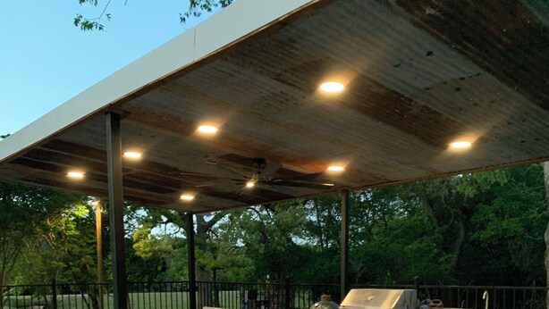 Un espace extérieur aménagé en terrasse, avec un barbecue, des sièges et une partie couverte.