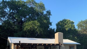 Un bâtiment d’un seul étage, doté d’un toit en métal, d’un porche à l’avant avec deux chaises et d’une enseigne indiquant « Lodge de pêche ».