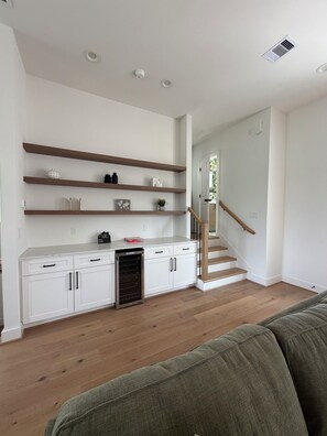 Ein modernes Wohnzimmer mit integrierter Küche, Holzböden, einer Treppe und einem Einbauofen.