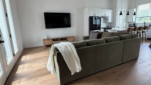 Una sala de estar moderna con un sofá grande, un televisor de pantalla plana y un ventilador de techo.