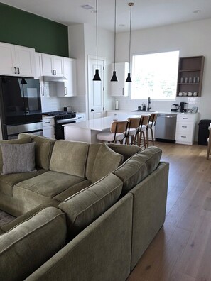 Eine moderne Küche mit weißen Schränken, einem schwarzen Kühlschrank und einem Essbereich mit einer Couch und Stühlen.