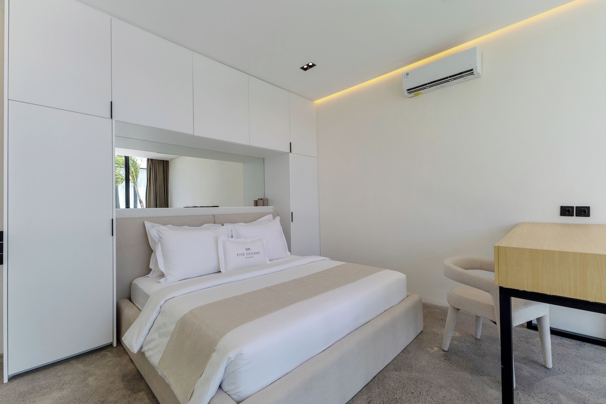 Una habitación de hotel moderna con una cama, un escritorio, una silla, un armario y un equipo de aire acondicionado.