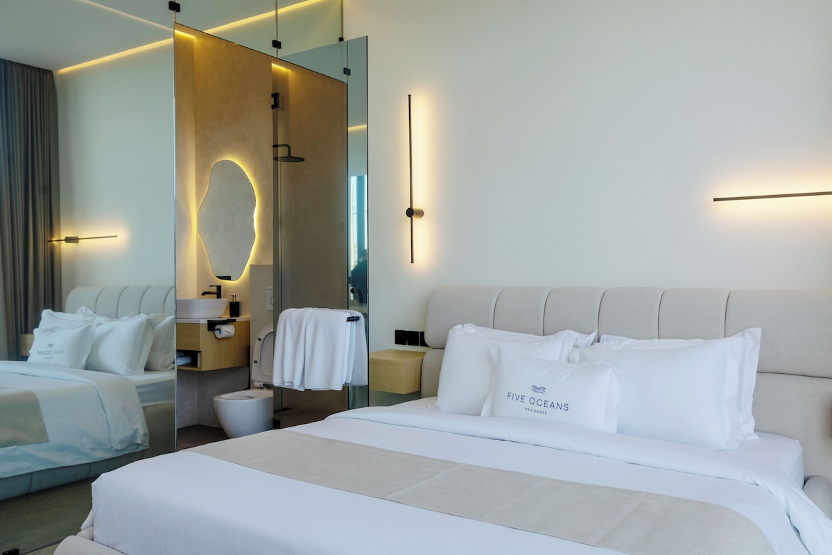A hotel room with a large bed, a bedside table, a mirror, and a bathroom.