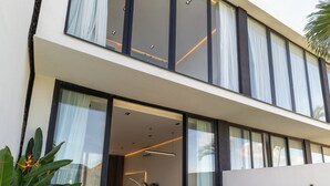 A modern two-story house with a swimming pool, large windows, and a patio area. - Five Ocean Residence (Badung)