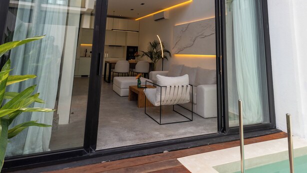 A modern two-story building with large glass windows, a pool, and a balcony with seating. - Five Ocean Residence (Badung)