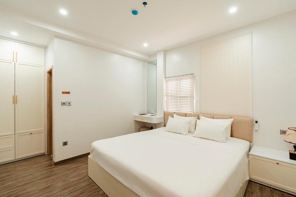 A hotel room with a bed, bedside table, nightstand, wardrobe, and a mirror.